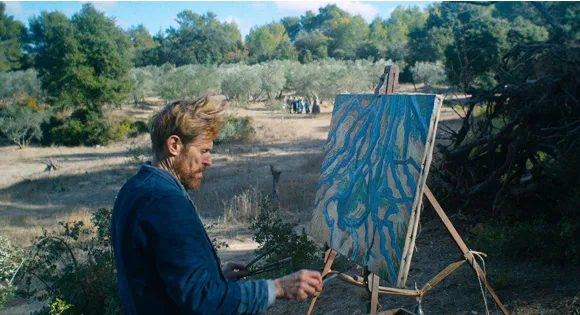 A painter at his easel in a dry field, working on an abstract canvas of blue lines over ochre.